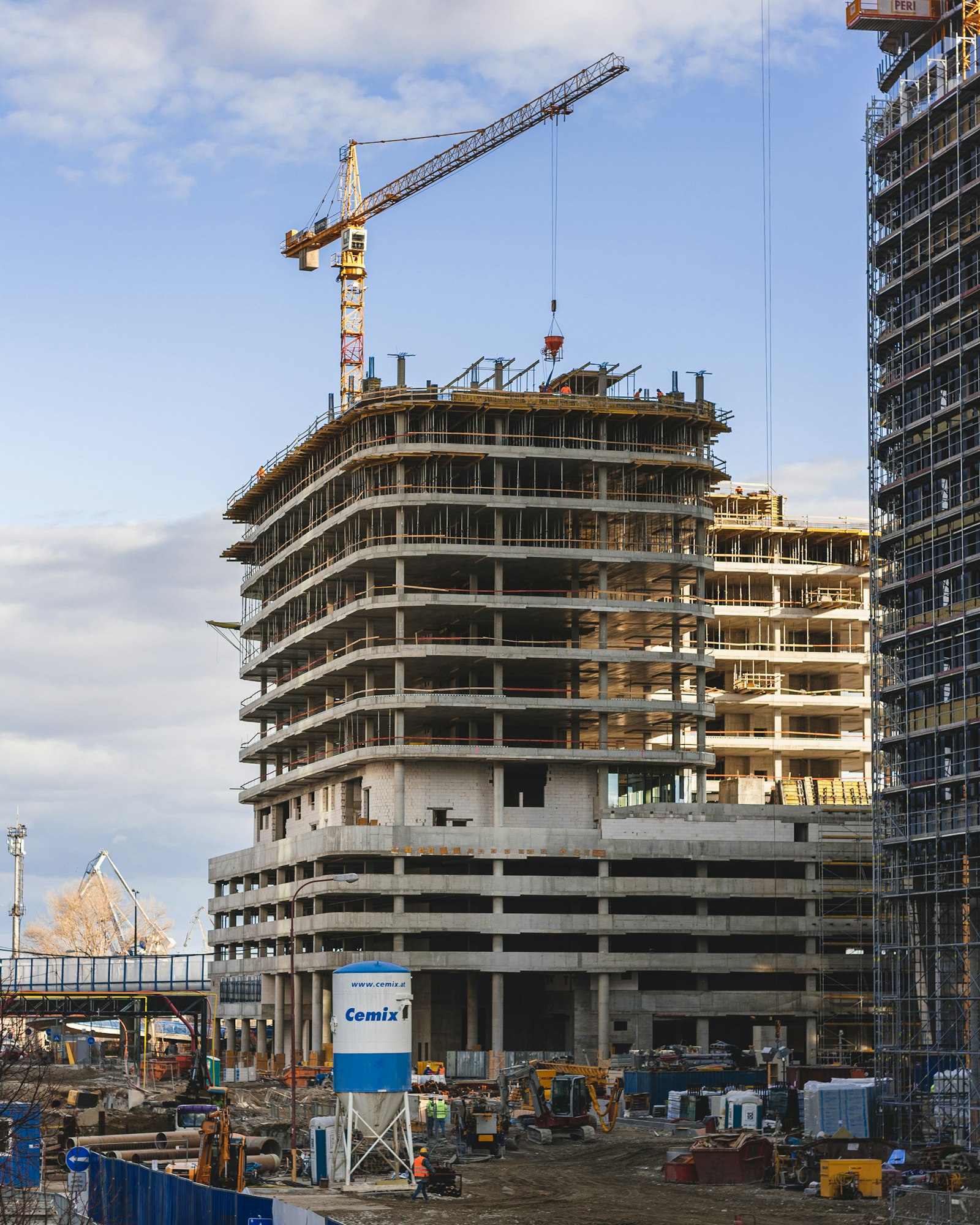 Rohbau eines mehrstöckigen Gebäudes mit Baukran im Hintergrund