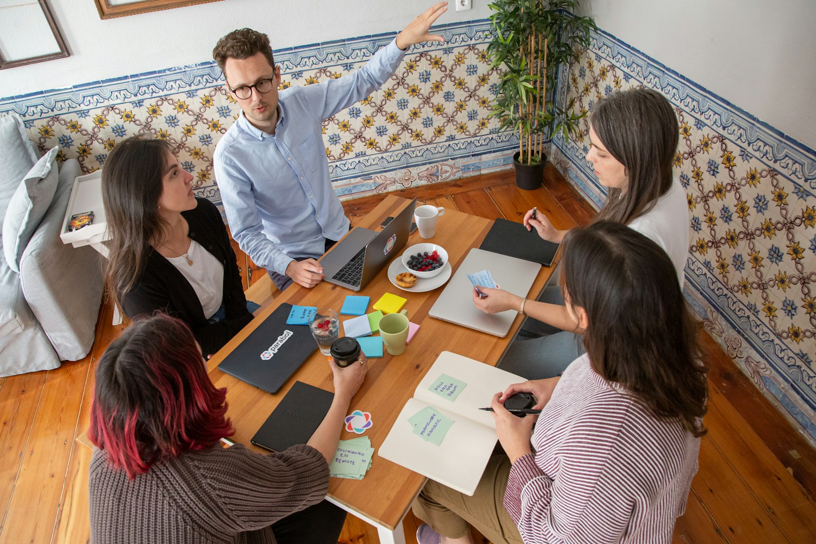 Team bei einem lebhaften Strategie-Meeting an einem Holztisch mit Laptops und Notizen